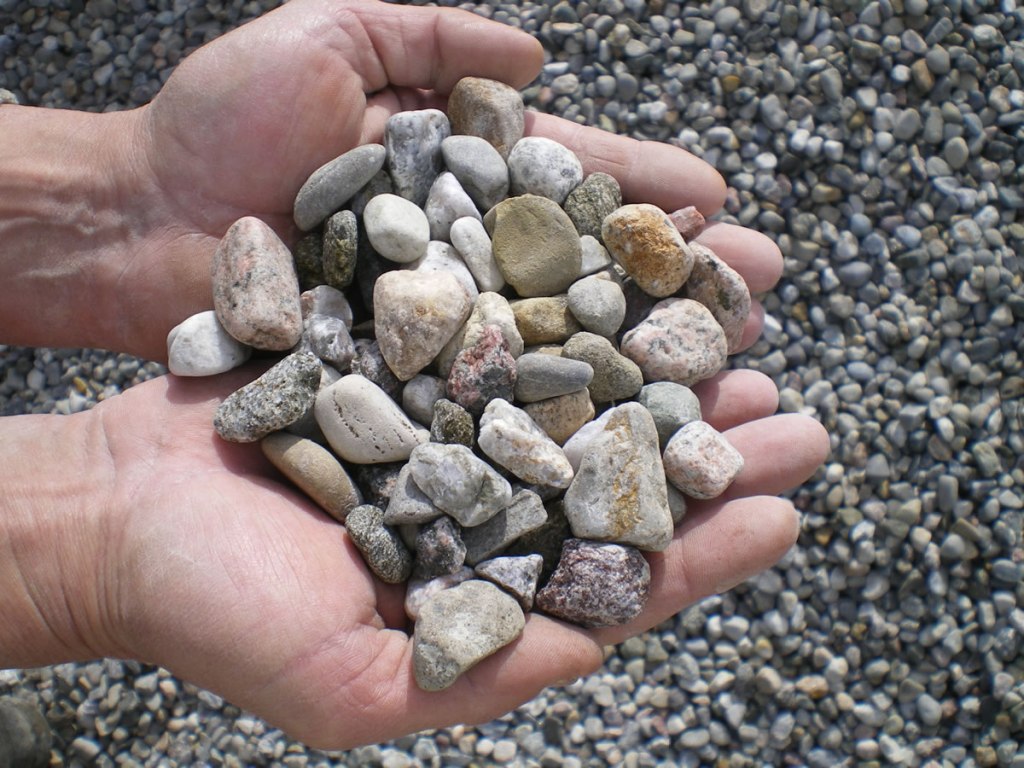 Washed riverstone in 1" sizing shown in a person's hands for scale